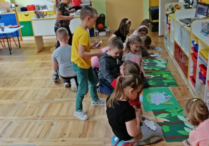 Dzieci uzupełniają plakat pt. Dżungla wyciętymi sylwetami zwierząt egzotycznych